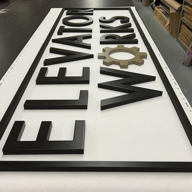 Elevator Works Black custom wood-look sign with carved and dimensional details